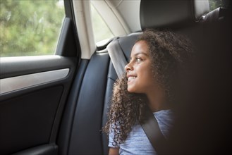 Smiling Hispanic girl in car looking out window
