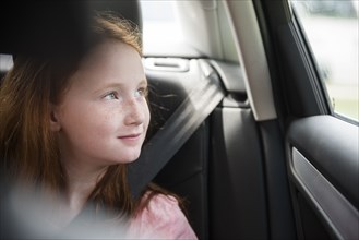 Smiling Caucasian girl in car looking out window