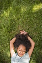 Smiling Hispanic girl laying in grass