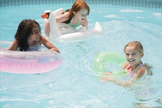 Smiling girls floating in swimming pool