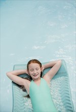 Caucasian girl floating on pool raft in swimming pool