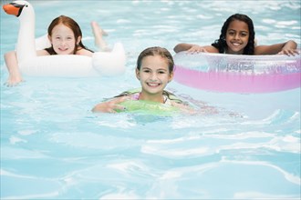 Portrait of smiling girls floating in swimming pool