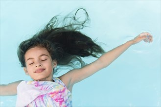 Smiling Caucasian girl floating in swimming pool