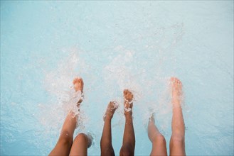 Legs of girls splashing feet in swimming pool