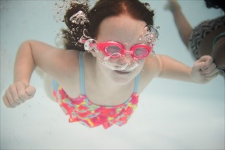 Girl swimming underwater wearing goggles