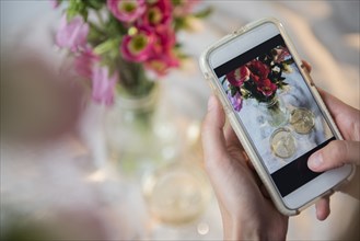 Caucasian woman photographing champagne and flowers with cell phone