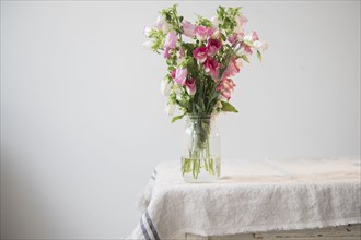 Flowers in jar of water at the edge of table