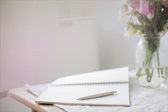 Pen on open blank notebook near flowers