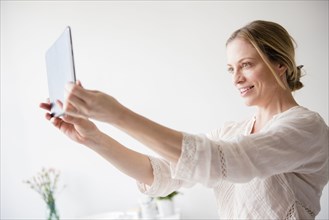 Caucasian woman posing for selfie using digital tablet