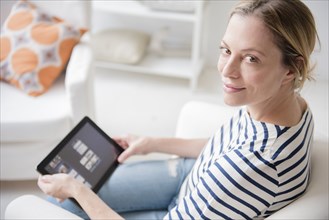 Caucasian woman sitting in armchair using digital tablet