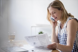 Caucasian woman reading paperwork talking on cell phone