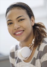 Portrait of smiling Hispanic woman wearing headphones around neck