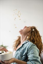 Caucasian woman throwing popcorn into mouth