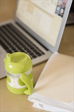 Sippy cup near file folder and laptop