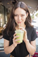 Thai woman drinking green smoothie