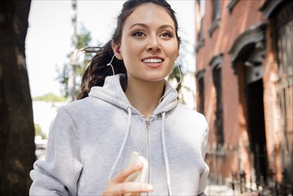 Thai woman jogging in city listening to earbuds