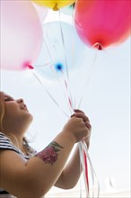 Caucasian girl with temporary arm tattoo holding balloons