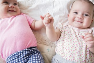 Caucasian twin baby girls smiling on bed