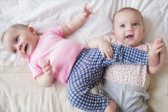 Caucasian twin baby girls playing on bed