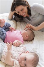 Caucasian mother touching nose of baby daughter on bed