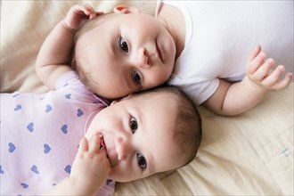 Caucasian twin baby girls laying on bed