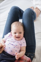 Caucasian baby girl laying on legs of mother