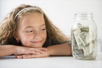 Smiling girl saving money in jar