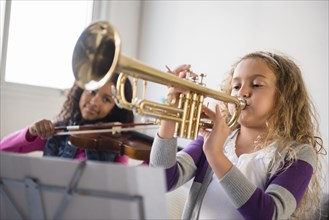 Girls practicing playing violin and trumpet