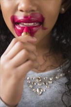 Mixed Race girl applying messy lipstick