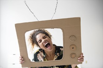 Mixed Race woman screaming in cardboard television