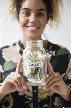 Mixed Race woman holding jar of budget money