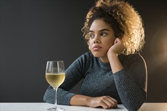 Bored Mixed Race woman wearing sweater drinking wine
