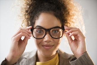 Mixed Race woman adjusting eyeglasses