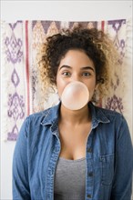 Mixed Race woman blowing bubble with gum