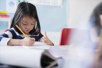 Girl counting with fingers and writing in notebook