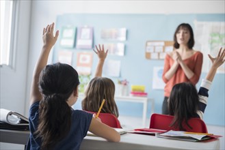 Girls raising hand for teacher in classroom