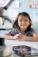 Smiling Asian girl leaning posing at desk