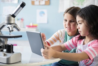 Caucasian girls sharing digital tablet in classroom