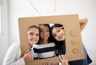 Portrait of smiling girls holding cardboard television