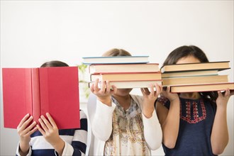 Girls holding books in front of faces
