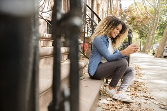 Mixed Race woman in city texting on cell phone