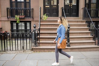 Mixed Race woman walking on city sidewalk