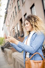 Mixed Race woman in city posing for selfie using digital tablet