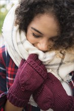 Mixed Race woman covering face with scarf