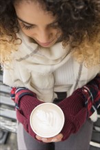 Mixed Race woman holding coffee cup with leaf in foam