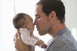 Hispanic father rubbing noses with baby daughter