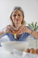 Caucasian woman cracking egg into bowl