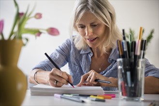 Caucasian woman sketching on pile of paper