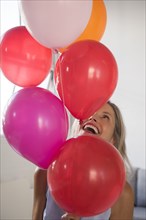 Smiling Caucasian woman holding multicolor helium balloons