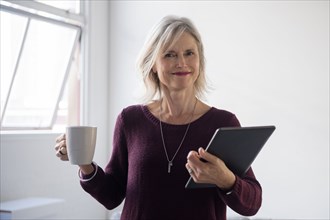 Portrait of Caucasian businesswoman holding coffee cup and digital tablet